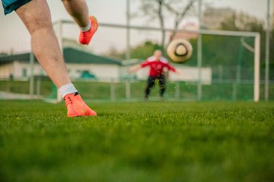 Ein Fussballer schießt einen Ball in ein Tor auf einem Rasenplatz